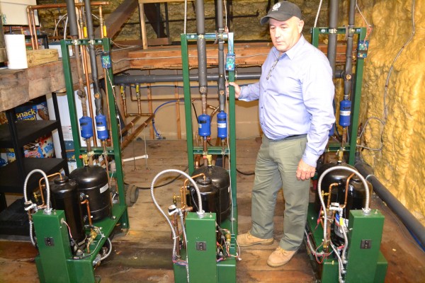 Jim LaBrecque stands in the attic of Tranten's in downtown Farmington, alongside three compressors. Those units refrigerate every cooler in the store, and transfer the heat energy to a heat pump that warms the building.
