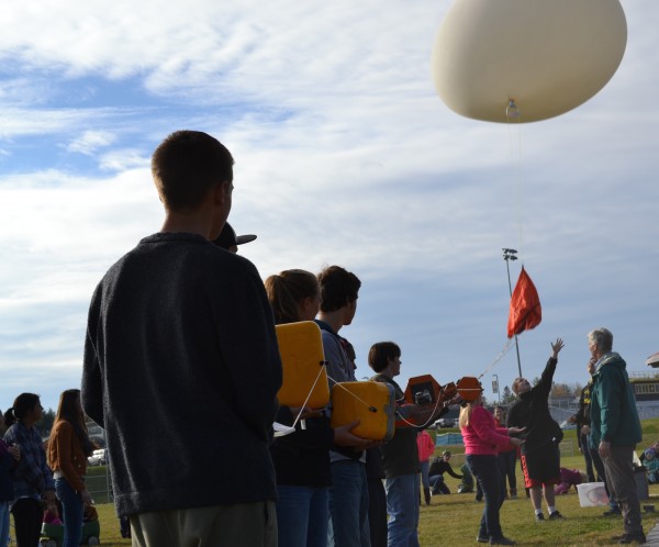 Mt. Blue High School student Austin Seeley lets the balloon go as Spruce Mountain and Mt. Blue students hold the payload boxes.
