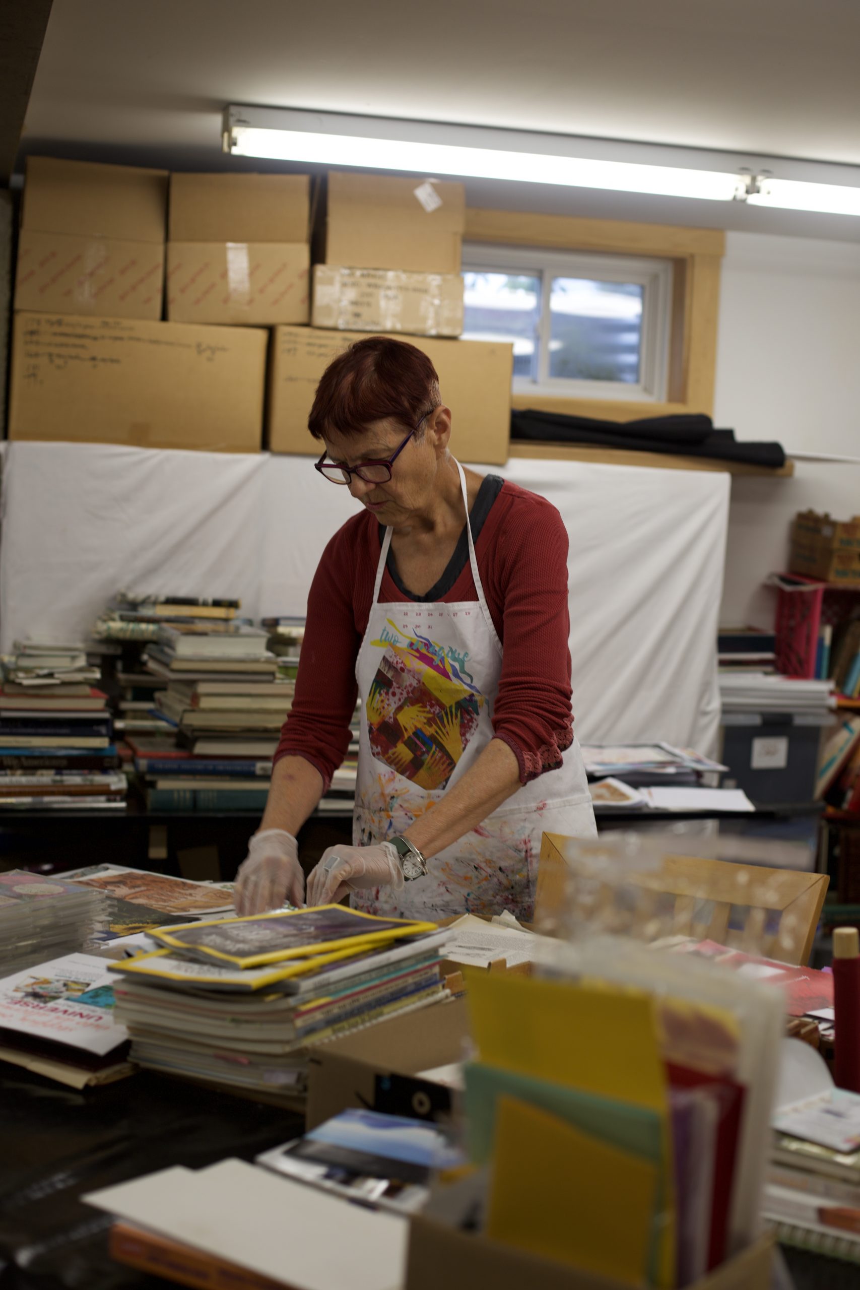 Meredith Mustard in the print making studio, surrounded by the used books she borrows images from.
